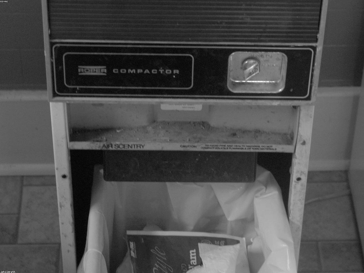 A realistic photo of a trash compactor in a domestic environment